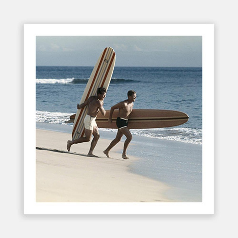 Young men running on beach with surfboard